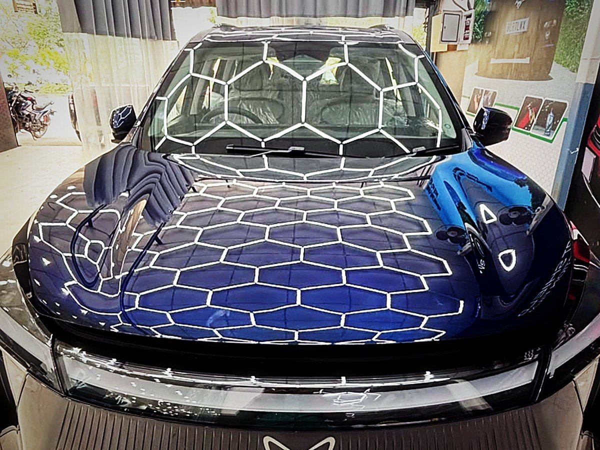 A dark blue Mahindra XEV 9e under hex studio lighting at Turtle Wax Studio Tellapur