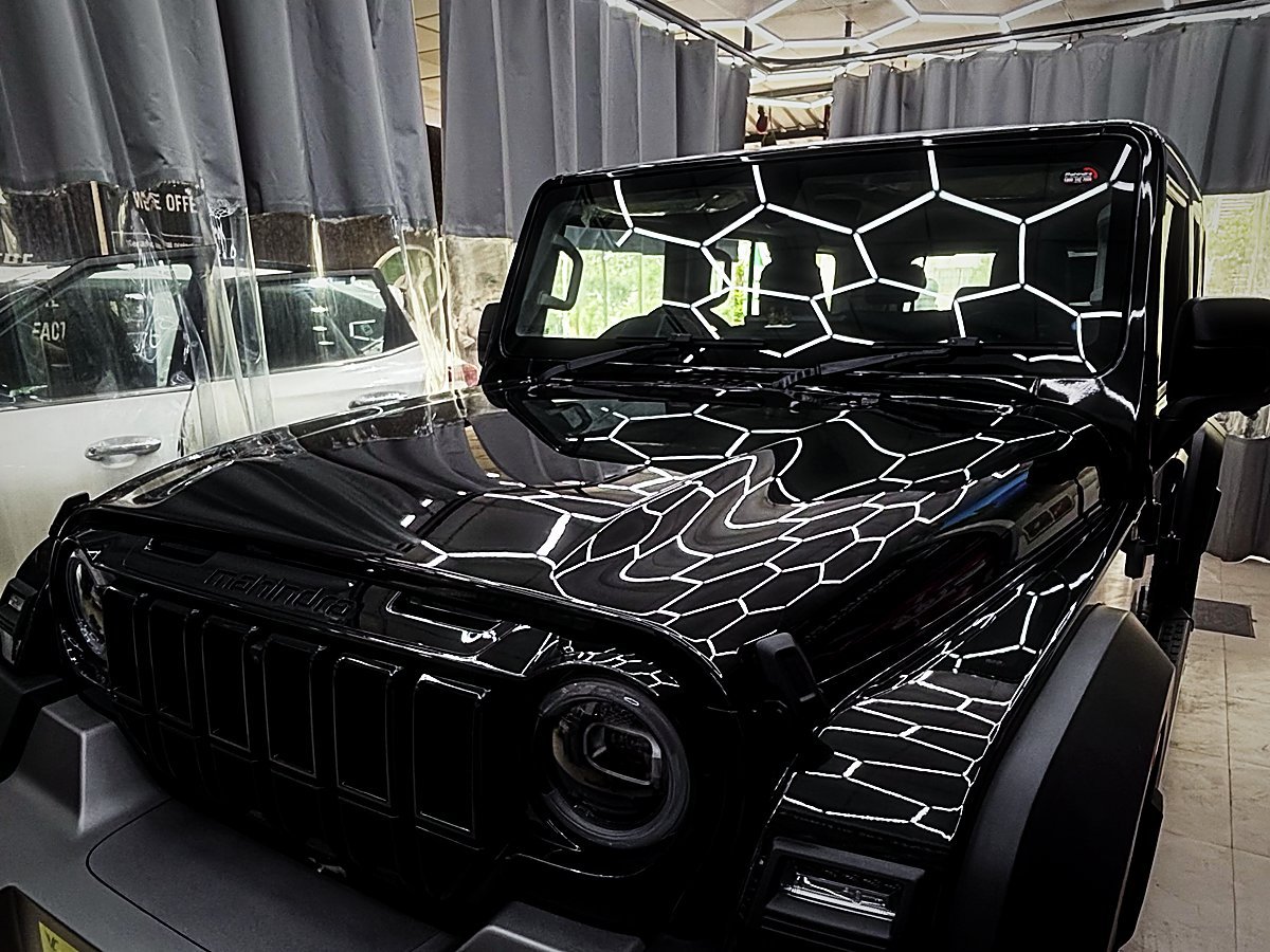 A freshly detailed black Mahindra Thar reflecting the hex ceiling lights at Turtle Wax Studio Tellapur